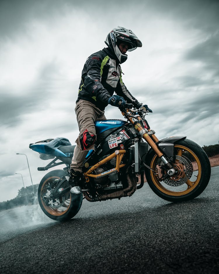 Man In Sports Leather Jacket And Helmet Riding A Sports Bike