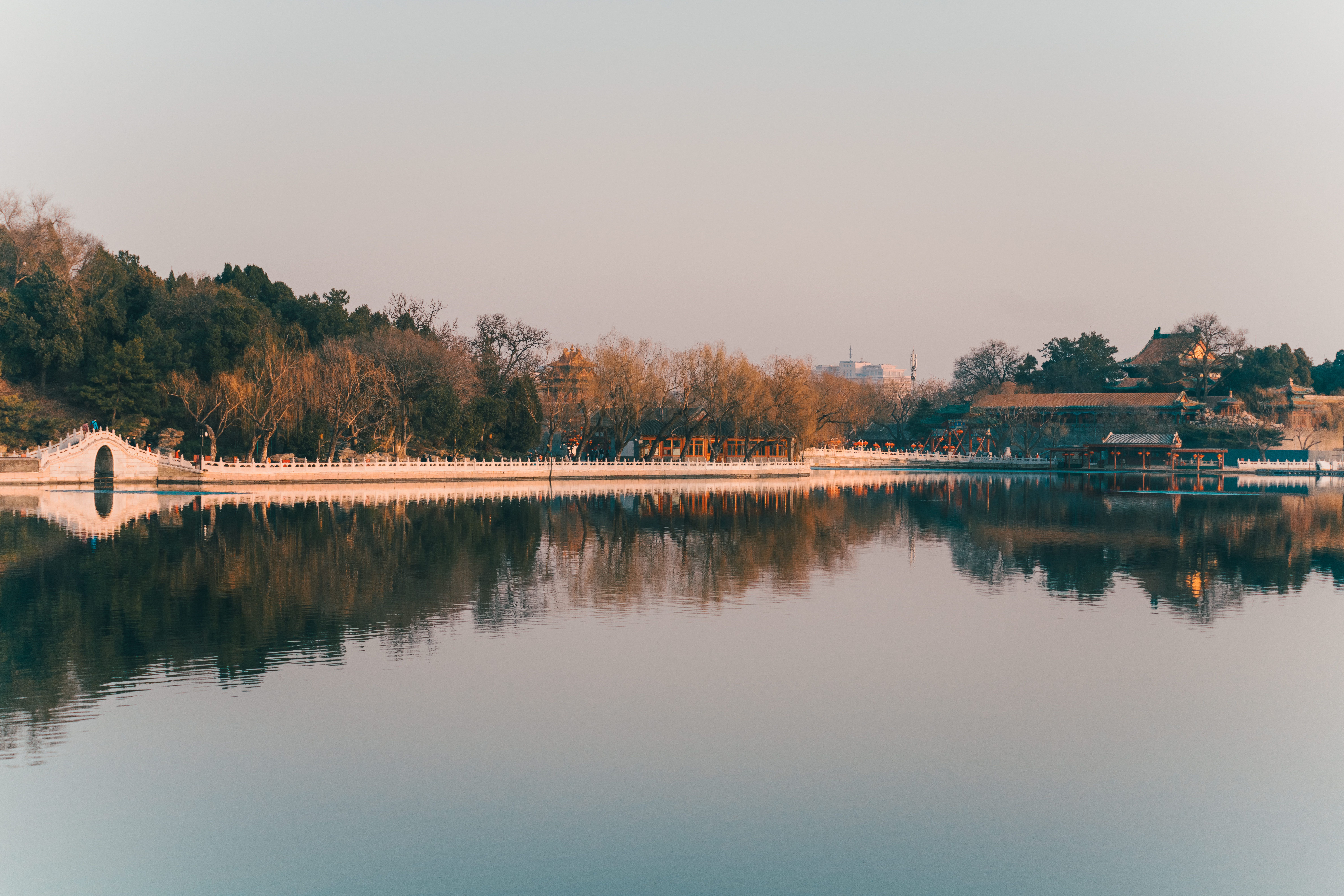 Reflective view of bridge and trees at sunset in Beijing's Summer Palace.