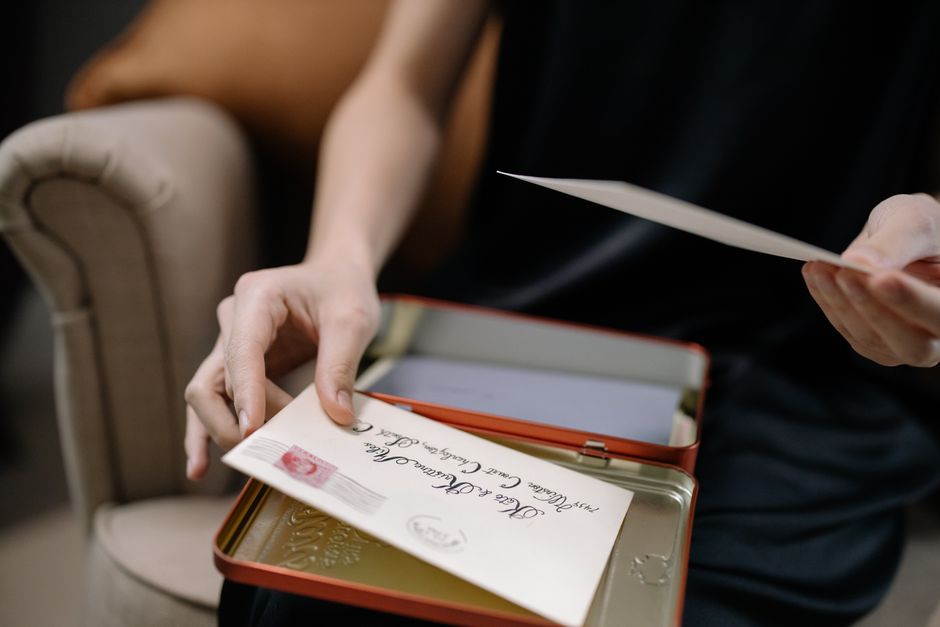 A person holds letters in a tin box, displaying vintage correspondence
