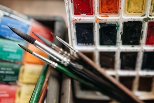 Close-up of paintbrushes with a vibrant watercolor palette set showcasing artistic creativity.