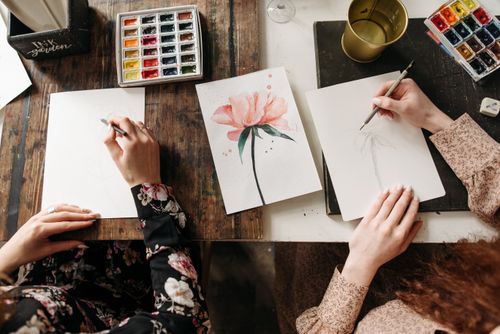 Free Overhead view of artists drawing floral designs with watercolors and pencils, indoors. Stock Photo