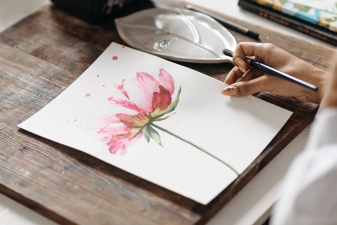 Free A Person Holding a White Paper with Flower Painting Stock Photo