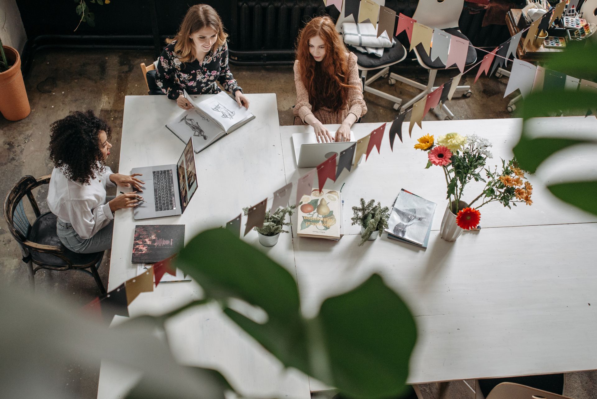 Top view of women working collaboratively at a decorated office table, fostering creativity and teamwork.
