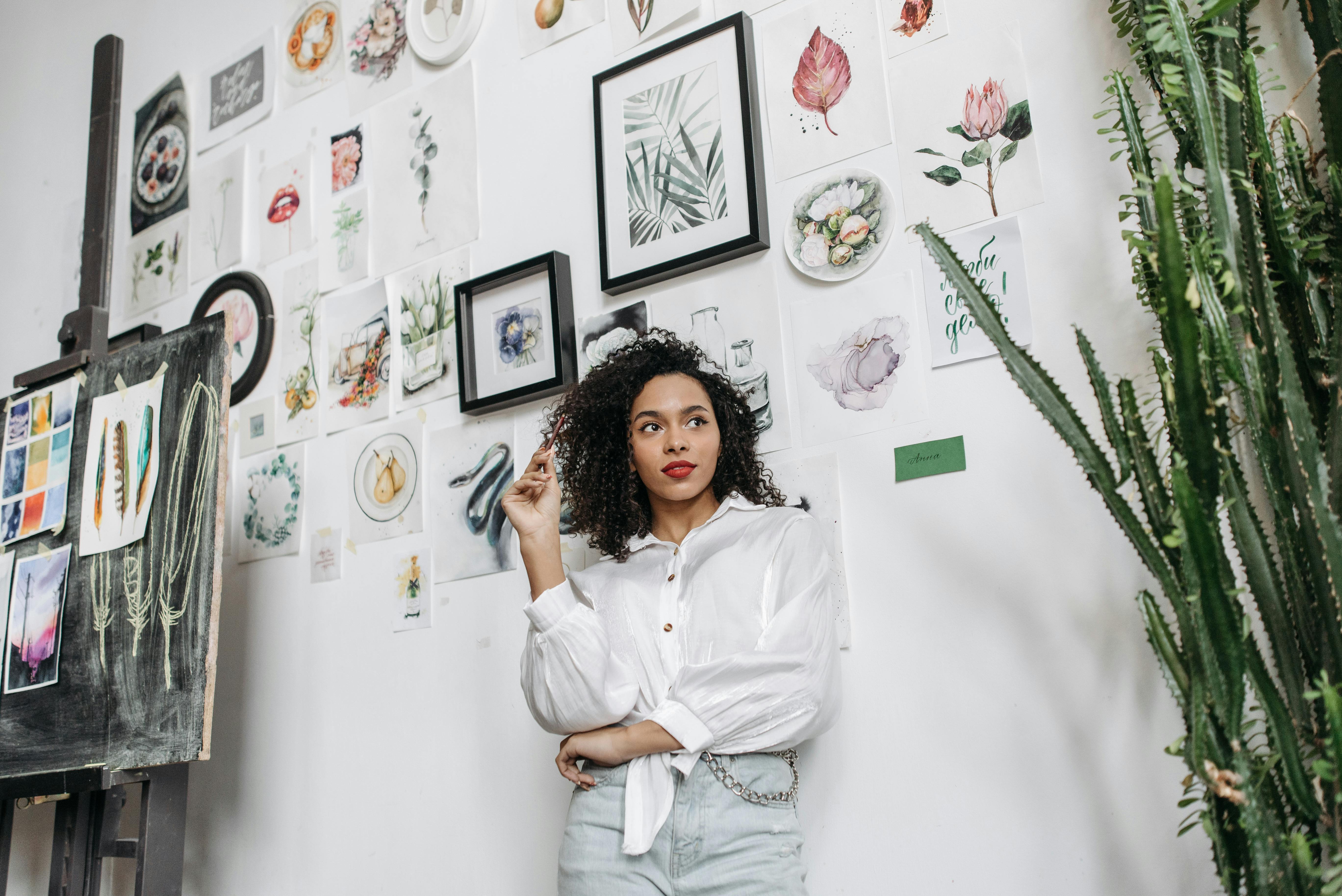 woman in white dress shirt standing near wall with paintings