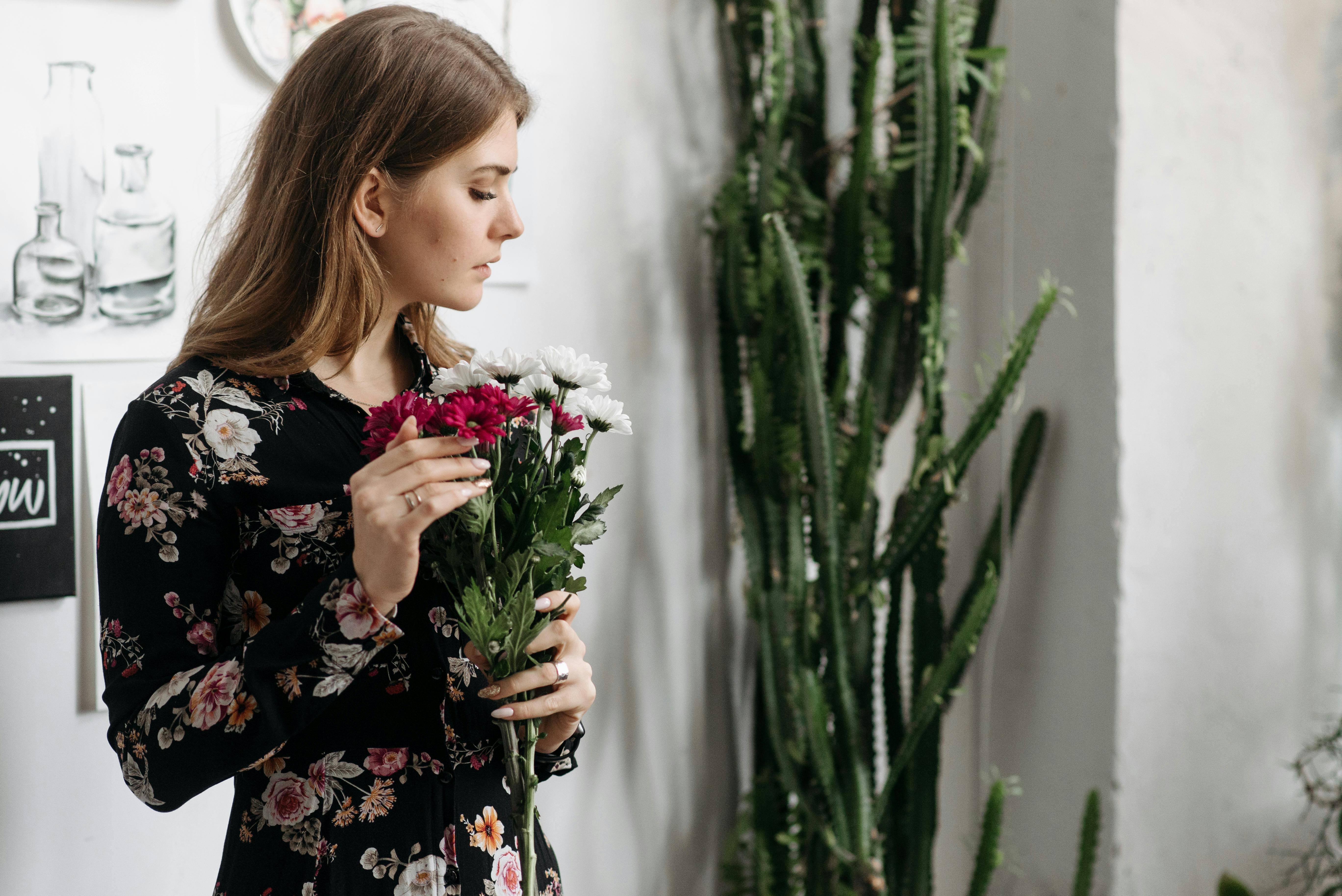 girl in black and pink floral dress holding white flowers