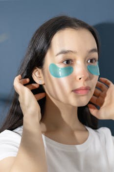 Asian woman applying under eye masks as part of a beauty regimen for skincare.