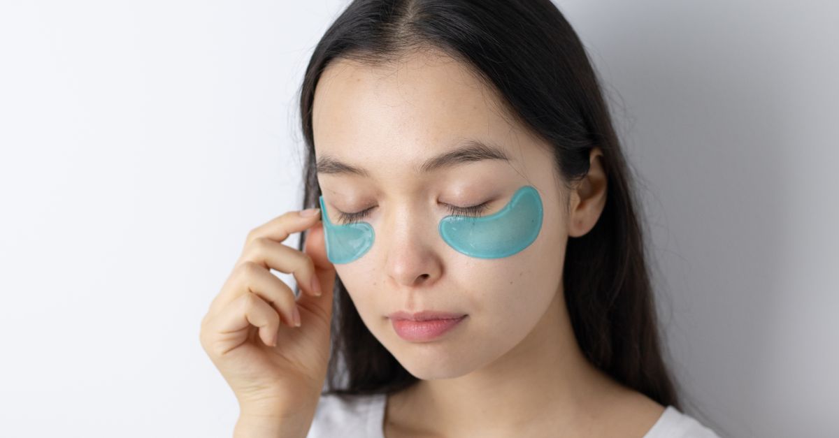 Serene Asian woman with closed eyes applying blue under-eye patches for skincare routine. - Evidence evidence guide for marine collagen skin hydration randomized trial