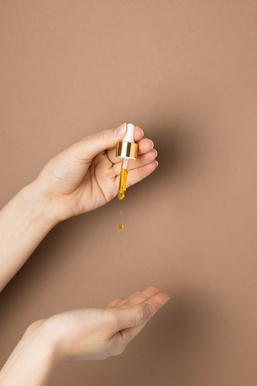 A Person Holding White and Gold Dropper