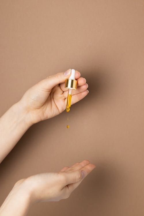 a-person-holding-white-and-gold-dropper