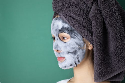 Side View of Woman With Sheet Mask and a Head Towel