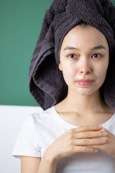 A woman with a towel on her head applies lip care during a skincare routine.