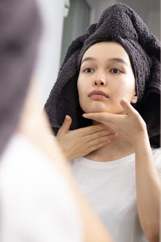 Woman performing self-care facial massage in front of a mirror.
