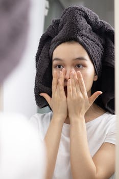 Close-up of a woman patting her face in the mirror, promoting skincare and relaxation at home.