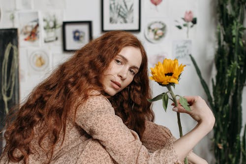 A Woman in Floral Top Holding a Sunflower