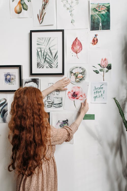 A Woman Putting a Paper with Drawing on the Wall