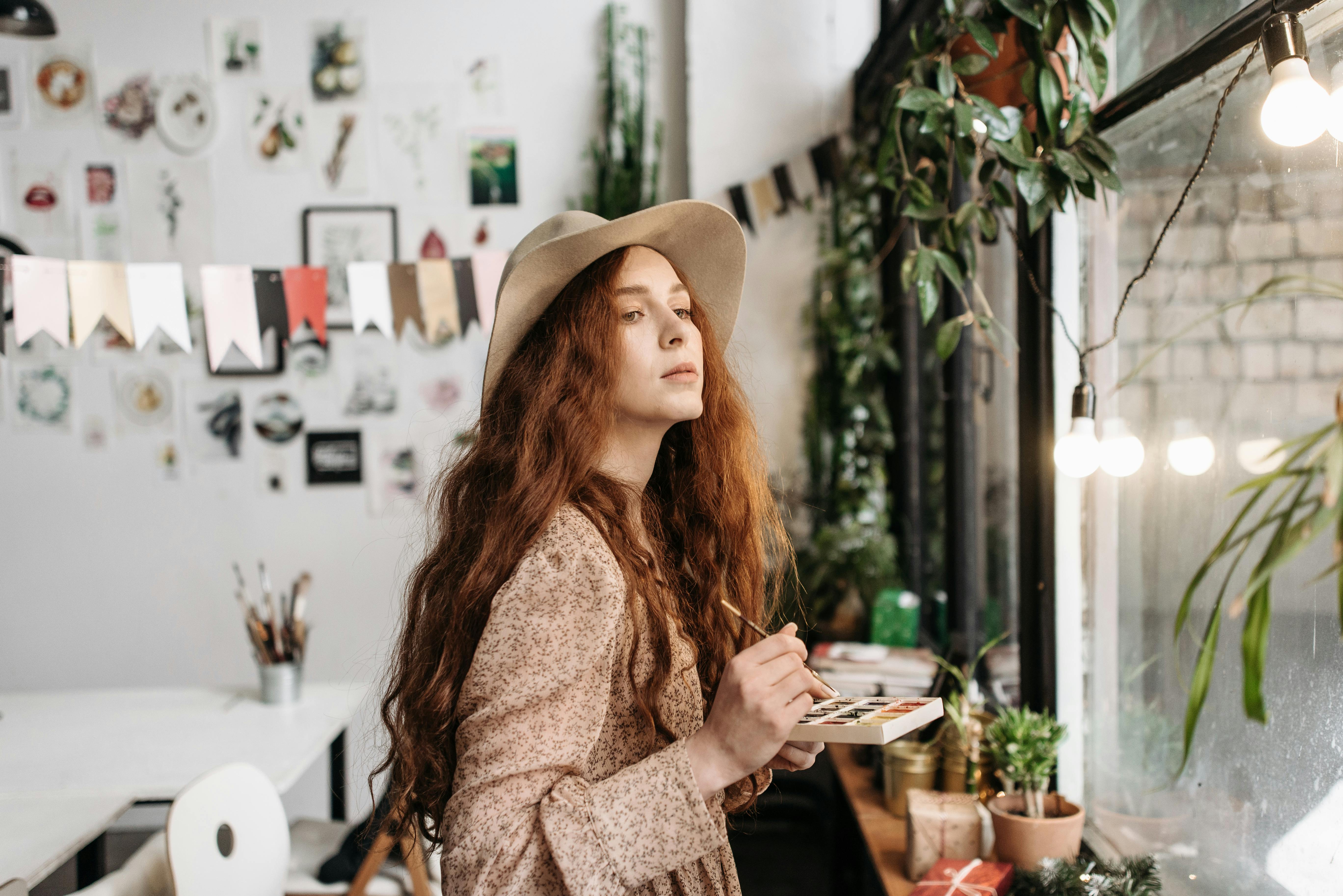 woman in brown and white floral long sleeve shirt wearing brown hat sitting on chair