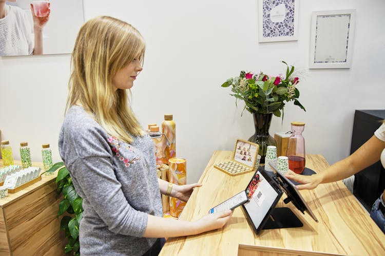 Woman With Mobile At Counter In Shop