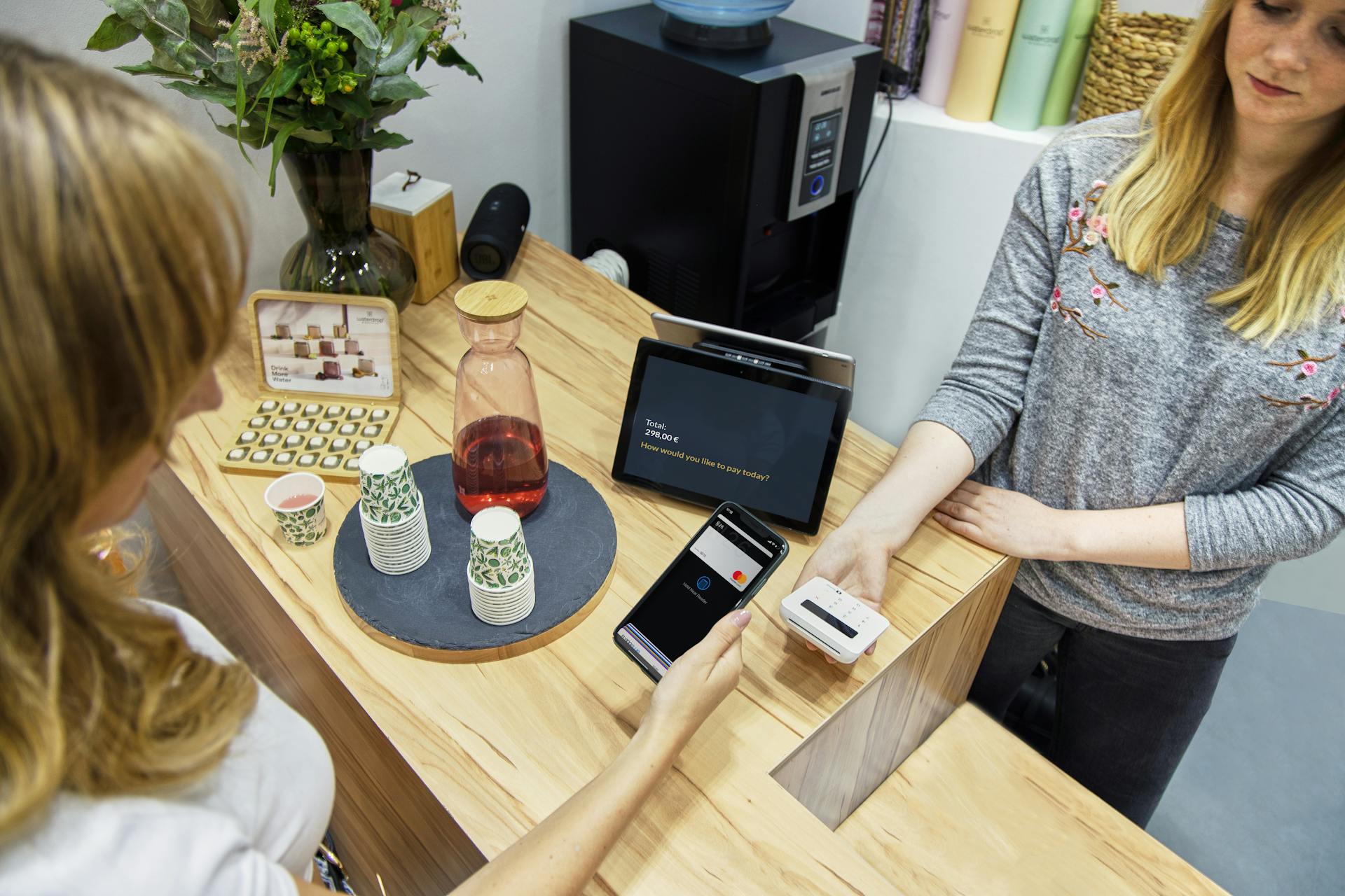 A woman makes a contactless payment at a stylish Berlin café, emphasizing technology and modern retail.