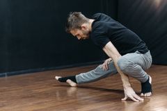 Mid-adult man stretching in a dance studio, emphasizing flexibility and balance.