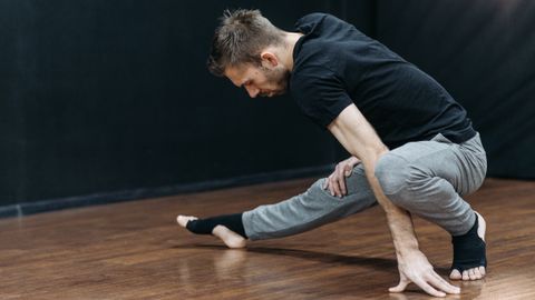 Mid-adult man stretching in a dance studio, emphasizing flexibility and balance.