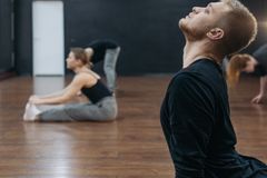 Portrait shot of adults stretching in a modern dance studio with wooden floors.