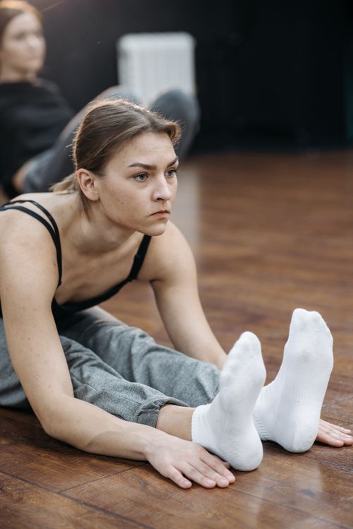 Free Woman performing seated leg stretch indoors, focusing on flexibility and exercise. Stock Photo