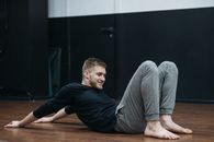 Man in Black Long Sleeve Shirt Sitting on Brown Wooden Floor