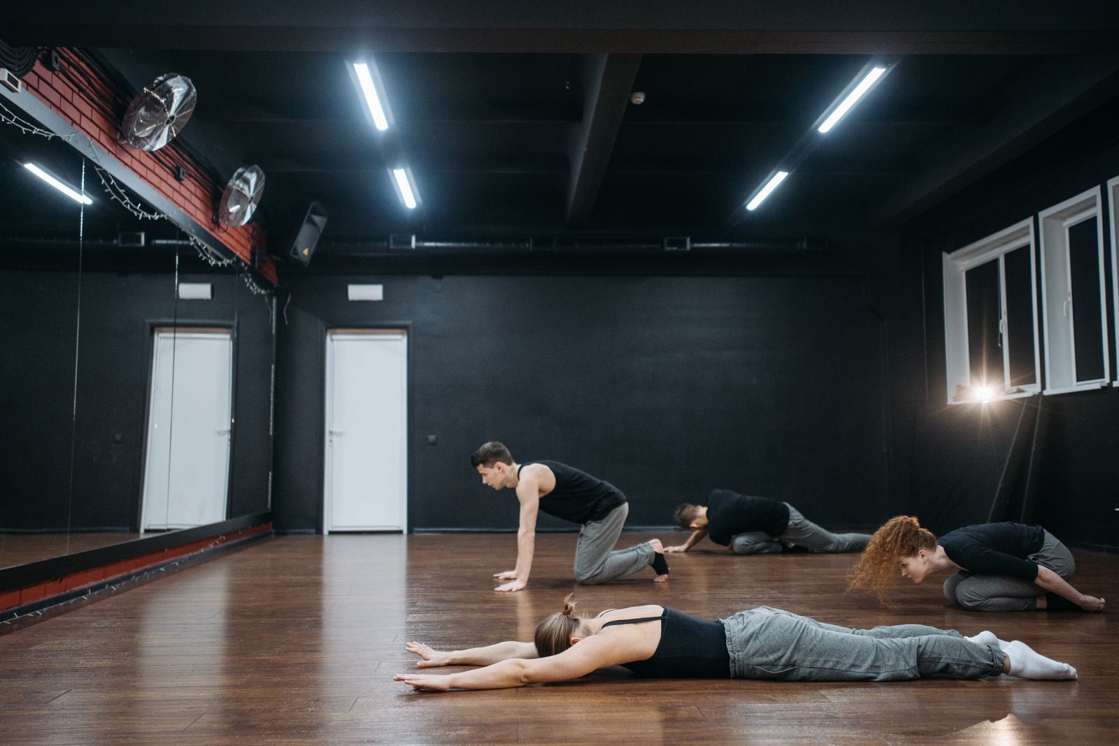 Floor-work class stretching on a warm wooden floor in a dark studio — photo by Pavel Danilyuk on Pexels