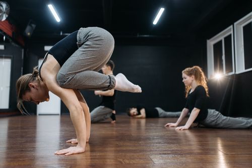 Free Group of dancers practicing acrobatic poses and flexibility exercises in a dance studio. Stock Photo