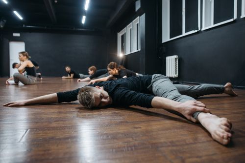 Free A group of adults practicing stretching exercises in a modern dance studio with wooden floors. Stock Photo