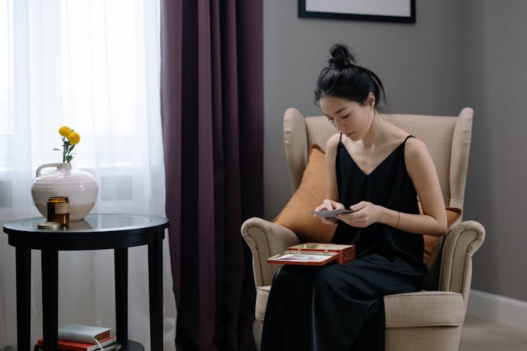 Woman In Black Silk Slip Dress Sitting On Beige Armchair