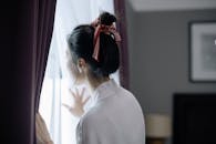 Woman with Hair Bun Looking Outside the Window