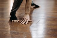 Person in Black Pants Sitting on Brown Wooden Floor