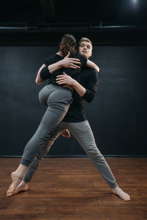 Free Two dancers embrace while leaping in a dance studio, showcasing emotion and flexibility. Stock Photo