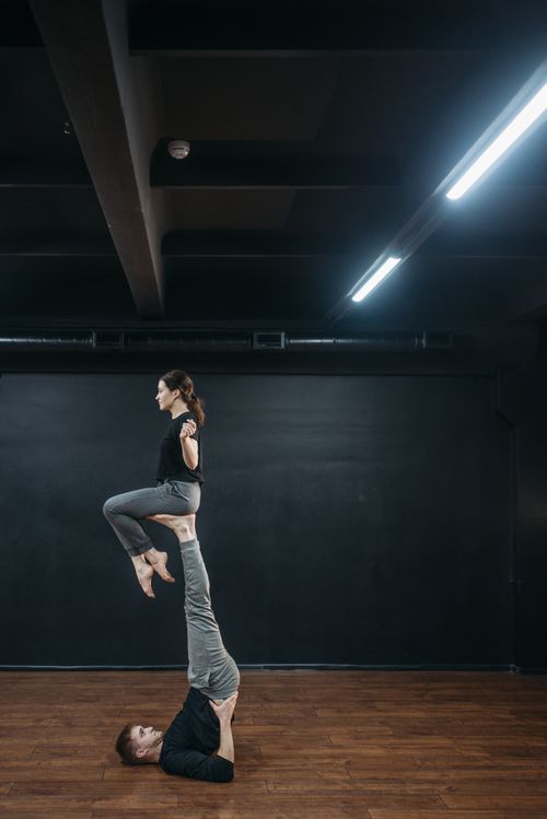 Free A couple demonstrating a balancing dance routine indoors on wooden flooring. Stock Photo
