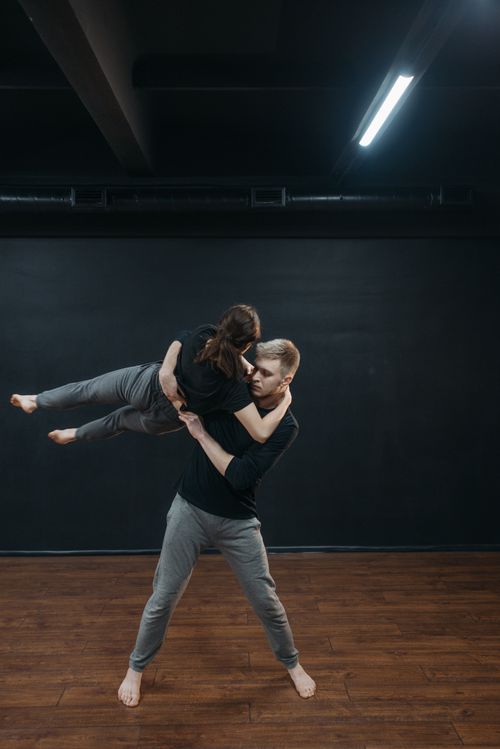 Free A couple performing an expressive dance routine in a studio with wooden flooring. Stock Photo