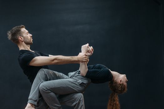 Man in Black T-shirt and Blue Denim Jeans Sitting on Gray Concrete Floor