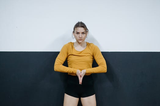 Young woman stands confidently with hands together, wearing yellow top.