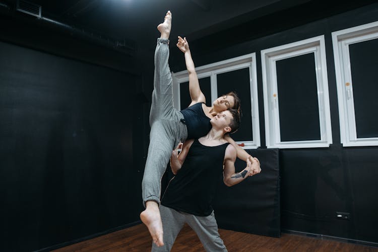 Man Carrying A Woman Doing A Leg Split 