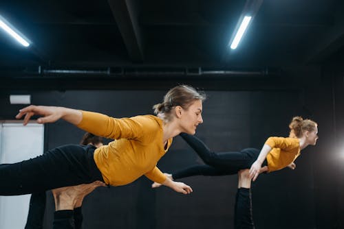 Free Women in Flying Position while Wearing Yellow Long Sleeves and Black Leggings Stock Photo