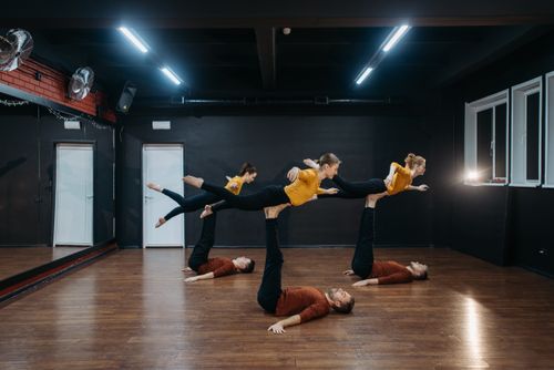 Free Five dancers showcase flexibility and balance in a dance studio during rehearsal. Stock Photo