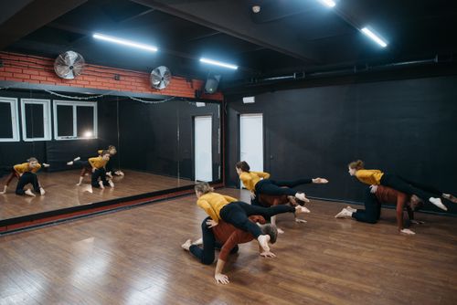 Free Group of dancers rehearsing contemporary choreography in a mirrored studio. Stock Photo