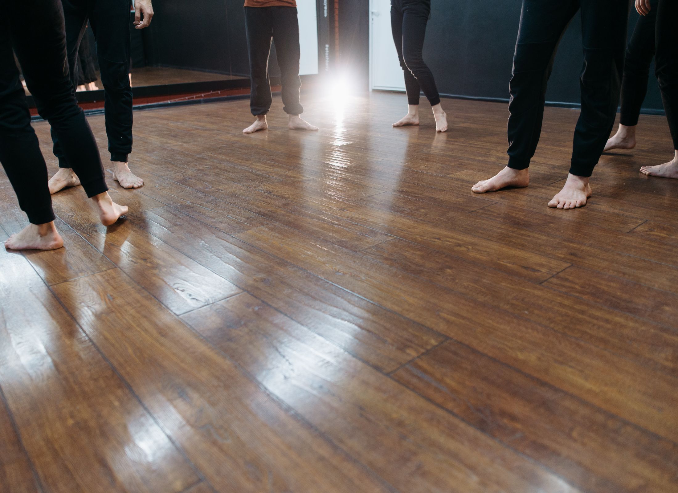 Bare feet on a warm, polished wooden studio floor.