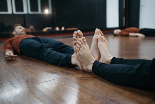 Free Person in Black Pants Lying on Brown Wooden Floor Stock Photo