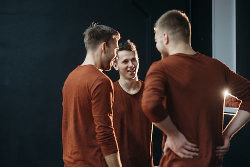 Free Three young men in casual brown attire share a light-hearted moment indoors. Stock Photo