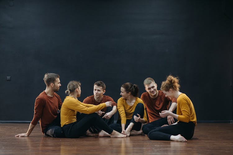 Group Of Dancers Sitting On Wooden Floor