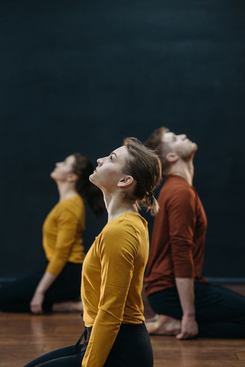 Free Adults in colorful attire meditate in a calm indoor yoga setting. Stock Photo
