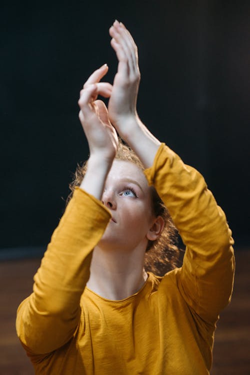 A Woman in Yellow Long Sleeve Shirt Raising Her Hands