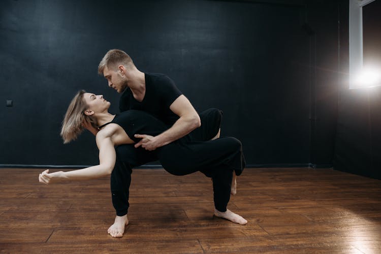 A Man Carrying A Woman In Black Tank Top While Looking At Each Other