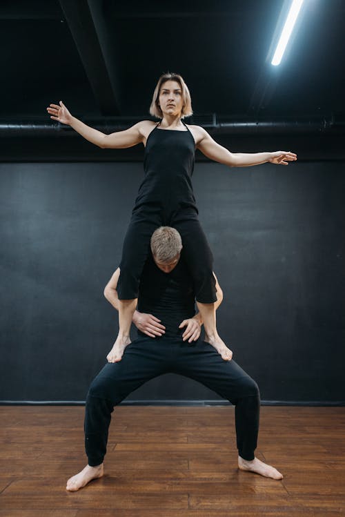 A Man Standing while Lifting a Woman in Black Pants